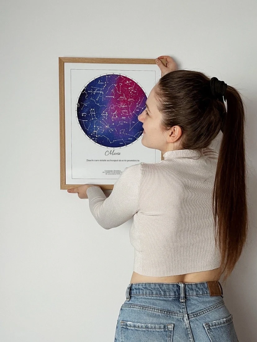 Un cuplu agățând pe perete un tablou cu stele, cadoul ideal de aniversare.